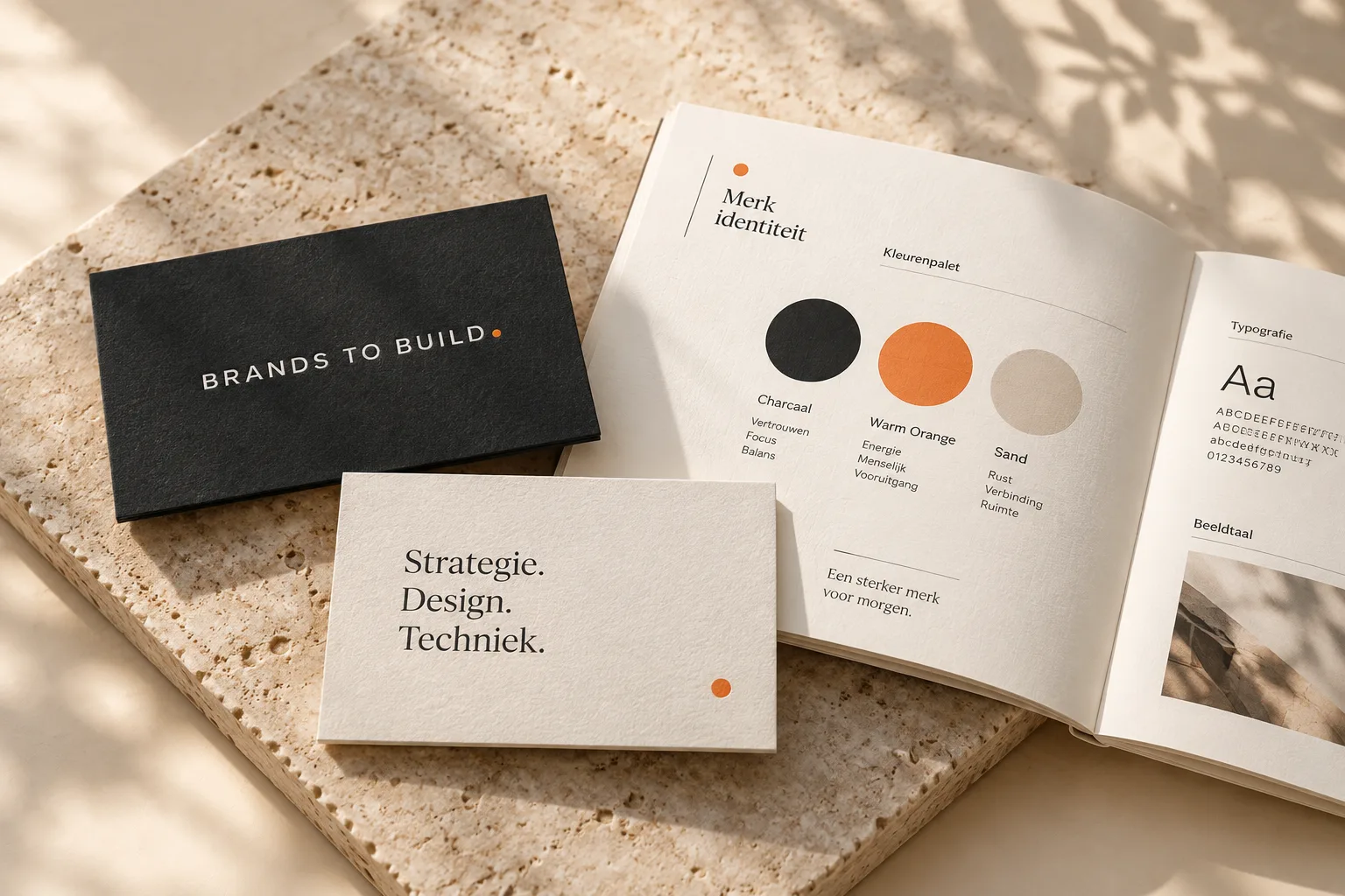 Een merkboek met kleurenpalet en typografie naast visitekaartjes met het logo van Brands to Build
