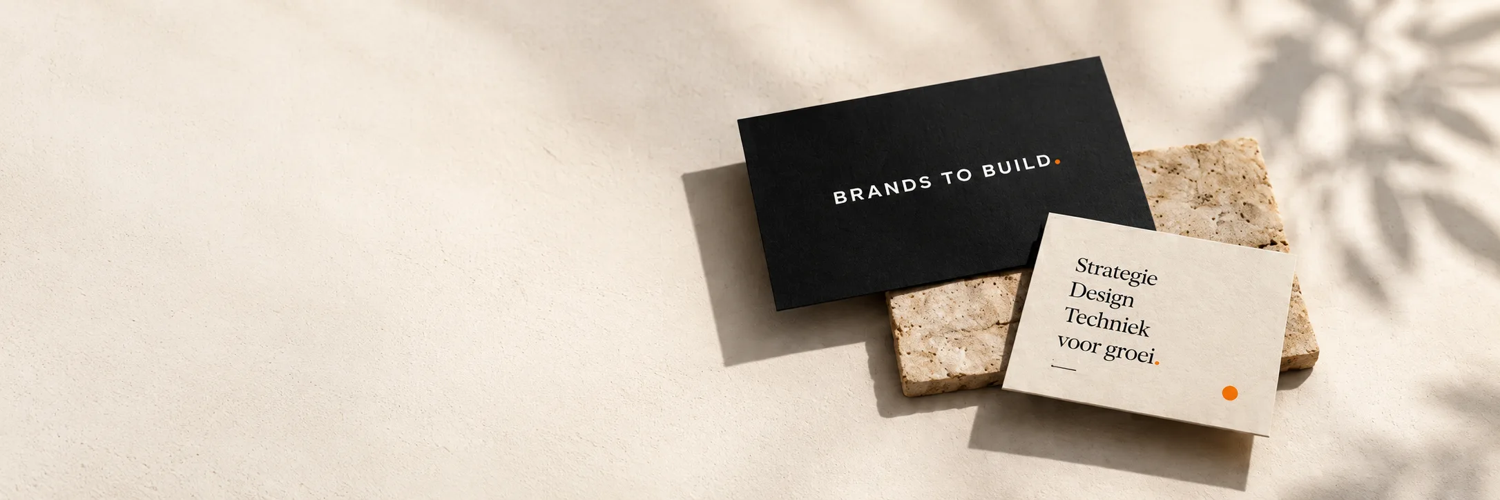 Merkidentiteit van Brands to Build: een zwarte kaart met het woordmerk en een crème kaart met de woorden Strategie, Design en Techniek, op een warme beige ondergrond